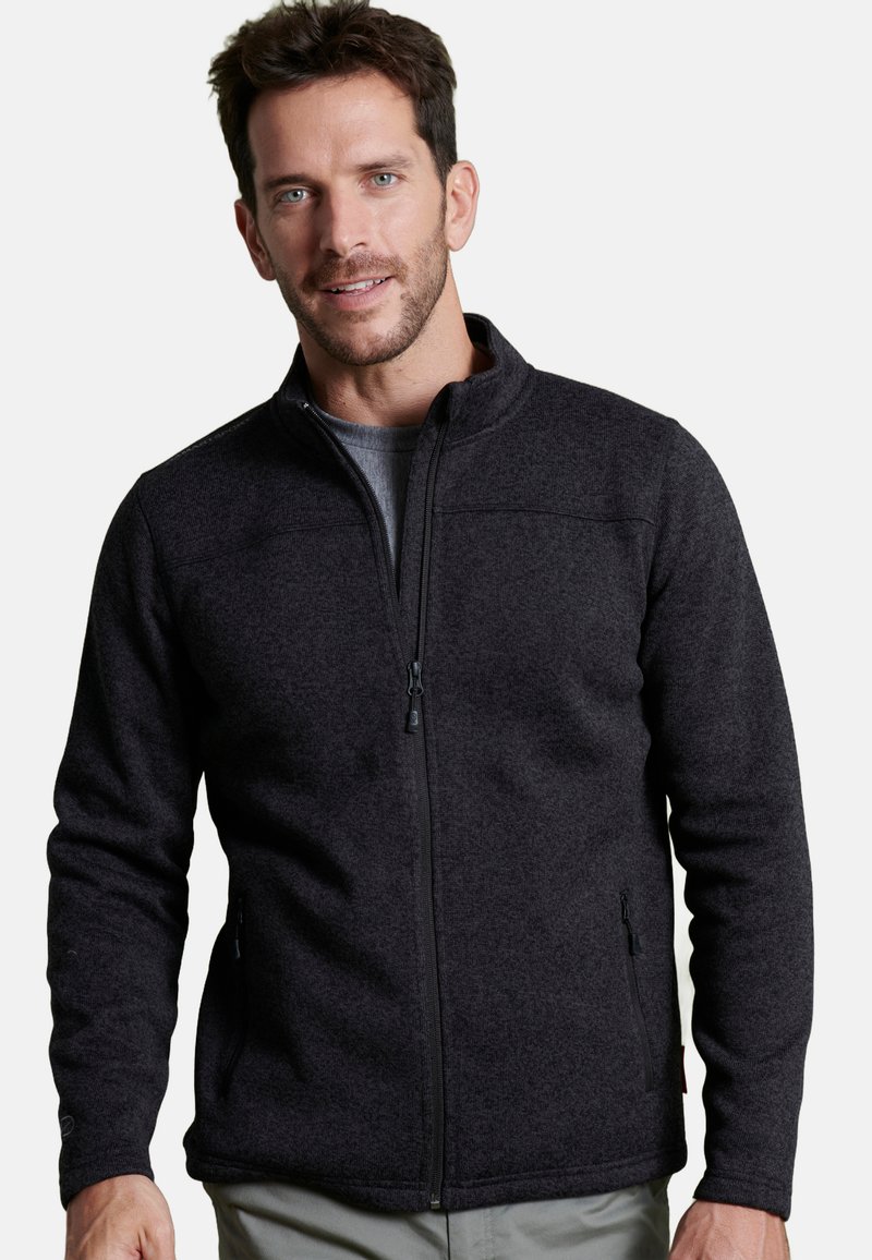 Giacca in pile nera con zip frontale, colletto alto e tasche laterali. Presenta una texture morbida e un design aderente.