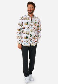 White button-up shirt with multicolored photo prints, paired with dark gray pants and white sneakers. The shirt features a classic collar.