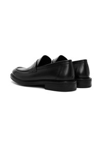 Mocassins en cuir noir avec une finition lisse, bout rond, talon bas et design minimaliste. Présente un détail de bande avant et un col rembourré.