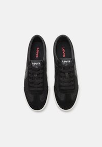 Schwarze lässige Sneaker mit Obermaterial aus Wildleder und Textil, weißer Gummisohle, runder Zehenpartie und schwarzen Schnürsenkeln. Branding auf der Zunge in Rot.