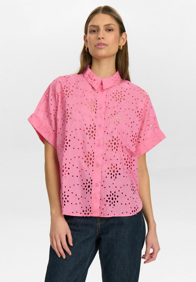 Camicia rosa a maniche corte con colletto a bottoni, caratterizzata da motivi ritagliati e una vestibilità ampia. Realizzata in tessuto leggero con una finitura strutturata.