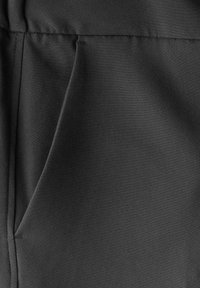 Tessuto nero che mostra una texture liscia con un discreto particolare della tasca laterale, caratterizzato da linee pulite e cuciture sottili.