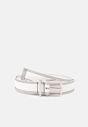 Ceinture en cuir blanc avec détaillé de couture noire et boucle métallique argentée, enroulée sur un fond gris clair uni.
