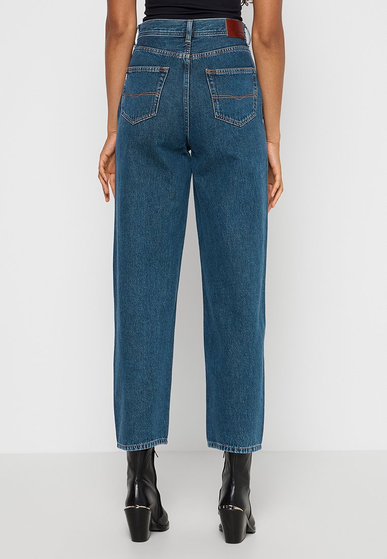 Hoge taille, wijde jeans in donkerblauwe denim met een gladde textuur. Bevat twee achterzakken en een bruine leren patch op de taille.