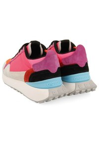 Zapatillas coloridas que presentan gamuza y malla en tonos rosa, morado y naranja, con una suela blanca y azul claro, cordones negros y detalles texturizados en el talón.