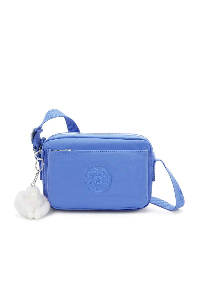 Blå nylon crossbody-väska med en framficka, justerbar rem och en vit pälsberlock. Har en cirkulär logotyp präglad på framsidan.