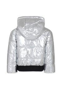 Giacca a vento argentata con cappuccio, caratterizzata da una texture lucida e un design a righe orizzontali. Dettagli in vita elastica nera nella parte inferiore.