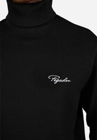 Czarny prążkowany sweter z wysokim kołnierzem, z białym haftowanym logo "Pegador" na klatce piersiowej, miękka tekstura i dopasowany krój.