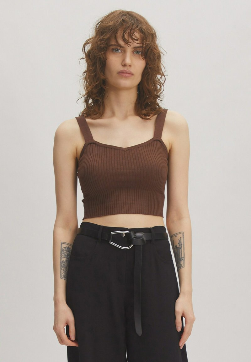 Brown ribbed crop top with wide straps and a square neckline, paired with high-waisted black trousers and a black belt featuring a silver accent.