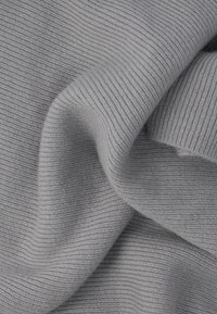 Hellgrauer, gerippter Strickstoff mit weicher Textur, der eine wellenförmige Drapierung und gleichmäßige horizontale Linien aufweist.