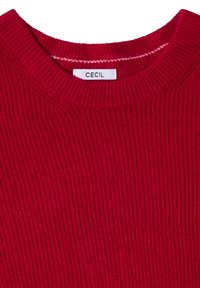Czerwony sweter z dzianiny o ribbowym wykończeniu. Ma okrągły dekolt oraz metkę z napisem "CECIL" wewnątrz kołnierza.