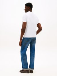 White short-sleeve t-shirt, blue denim jeans, rolled cuffs, and dark brown loafers. Simple, classic design, visible stitching details.