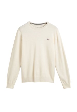 Crème-kleurige gebreide trui met lange mouwen en een ribgebreide onderrand, met een klein geborduurd logo op de borst. Soepele textuur.