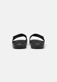 Sorte sandaler med vevde teksturerte stropper, flate såler og minimalistisk design. Har justerbare festemidler for en sikker passform.