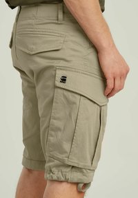 Shorts cargo color khaki realizzati in cotone resistente, dotati di tasche laterali, polsini elasticizzati e una etichetta con logo sulla gamba. Tessuto liscio e vestibilità sartoriale.