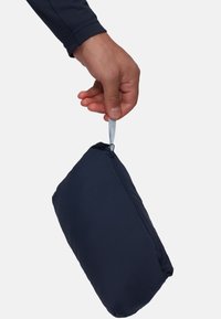 Navy fabric pouch held by a hand, featuring a zip closure with a pull tab; soft texture and rectangular shape designed for portability.