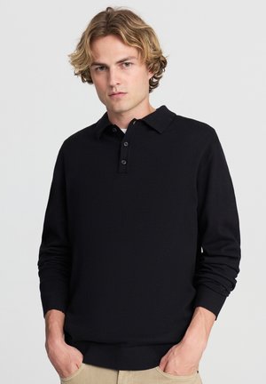 Maglione polo nero realizzato in tessuto morbido, con colletto classico, patta con tre bottoni e polsini a coste. Vestibilità su misura, dettagli minimi.