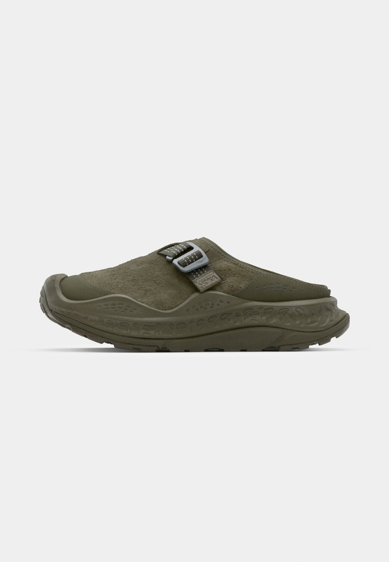 Olive green slip-on shoe with a textured upper, adjustable dual buckles, and a chunky rubber sole featuring a patterned design.