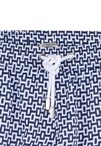 Costumi da bagno blu e bianchi con elastico in vita, cordino e accessori in argento. Design geometrico che ricopre il tessuto principale.