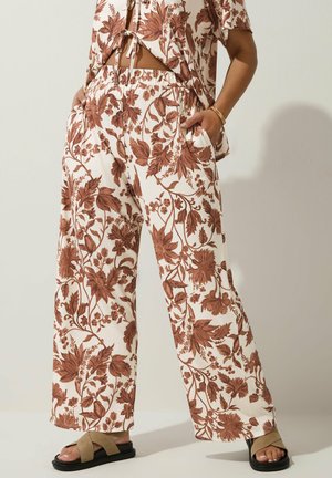 Floral patterned wide-leg trousers in cream with rust-colored leaves. Features an elastic waistband and side pockets. Complemented by black sandals.