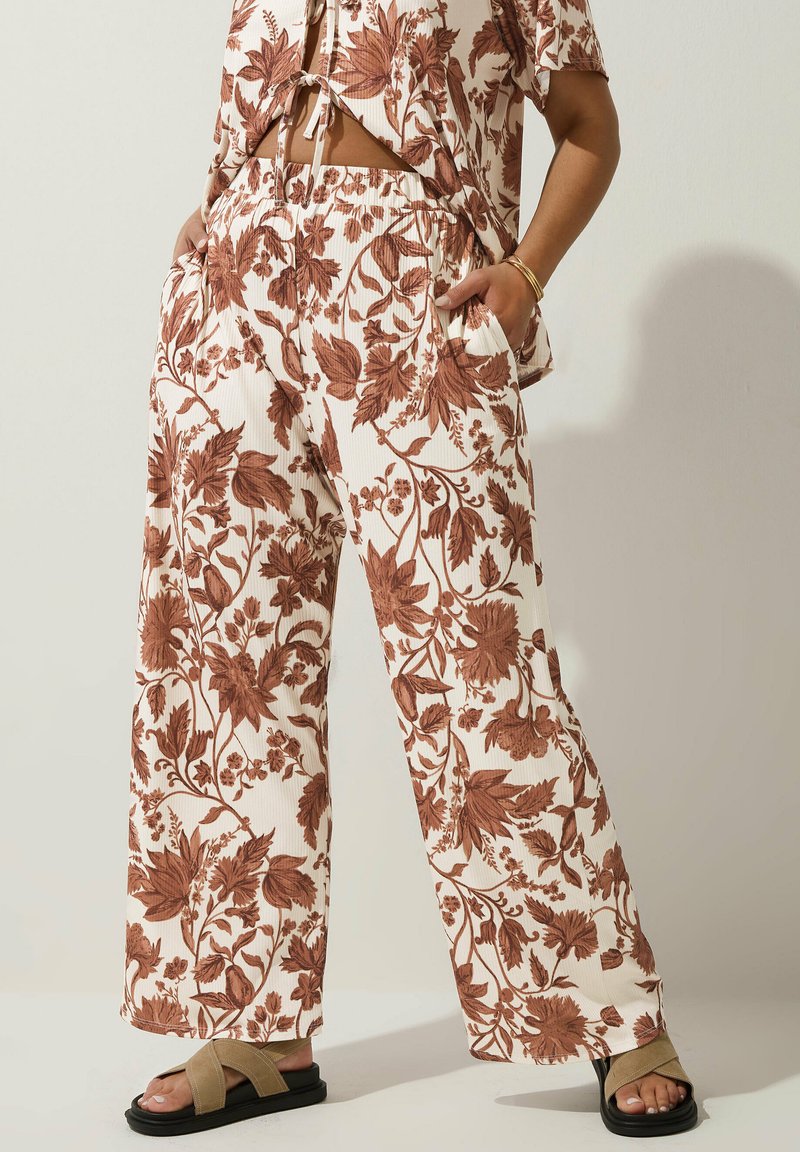 Blommönstrade vida byxor i krämfärg med rostfärgade löv. Har resårmidja och sidofickor. Kompletteras av svarta sandaler.