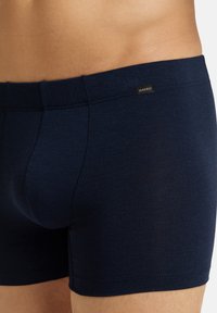Boxer cortos azul marino hechos de una tela suave, con un diseño ajustado, costuras cosidas y una pequeña etiqueta de la marca en la cinturilla.