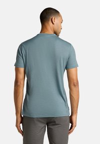 Men's fitted short-sleeve t-shirt in light blue, made of soft material. Flat seams, crew neck, and a tag on the lower side. Textured finish.