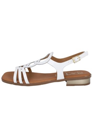 Sandalia plana blanca con diseño floral recortado, correa ajustable en el tobillo con hebilla dorada, plantilla acolchada color tostado y tacón bajo.