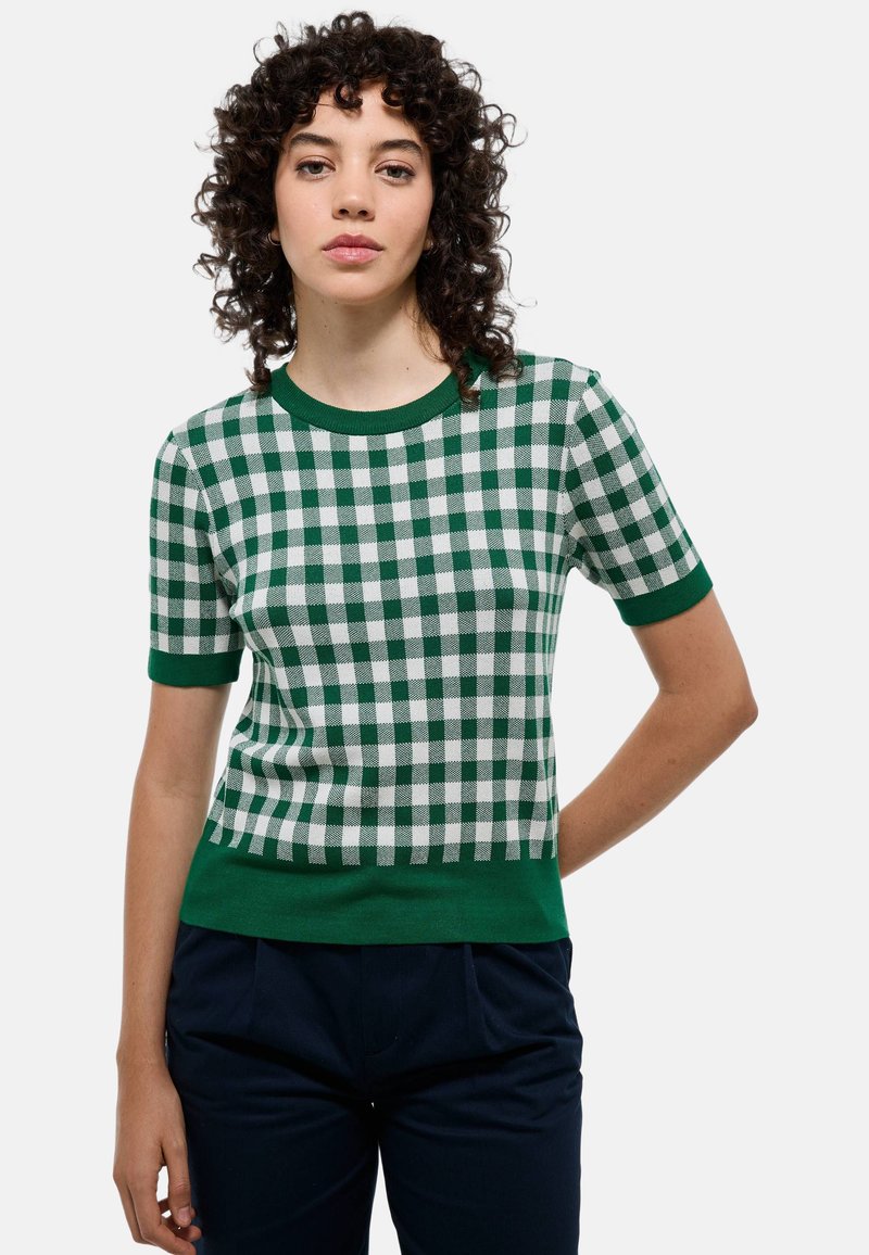 Pull à manches courtes à carreaux verts et blancs avec un col rond et des bords côtes au niveau des poignets et de l'ourlet, en tissu tricoté.