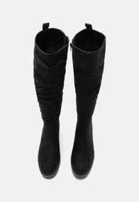 Sorte semskede knelang støvler med en slouchy design, glidelås-lukking og flat såle. Teksturen er glatt med en matte overflate.