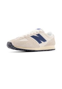 Μπεζ σουέντ αθλητικό παπούτσι με ναυτικό μπλε λεπτομέρειες, σχεδιασμό με κορδόνια και υφή στην επάνω επιφάνεια. Διαθέτει μαύρη λαστιχένια σόλα για πρόσφυση. Κλασικό αθλητικό στυλ.