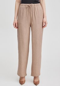 Beiga linbyxor med elastisk midja och justerbar dragsko. Modell med vida ben och texturerad yta samt en avslappnad passform.