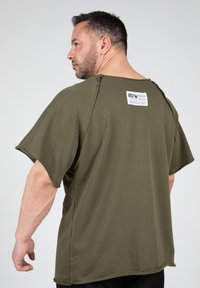 Olijfgroen oversized t-shirt met korte mouwen, onafgewerkte randdetails en een wit label op de achterzijde. Gemaakt van zacht katoen.