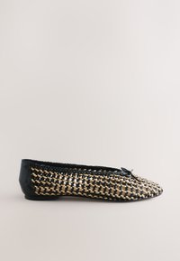 Chaussure plate tissée noir et fauve avec bout fermé, petit talon et petit nœud sur le dessus, présentée sur un fond uni.