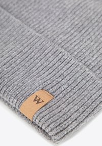 Berretto in maglia grigio con trama a coste, dotato di una toppa in pelle con un logo. Materiale morbido e design aderente per garantire calore.