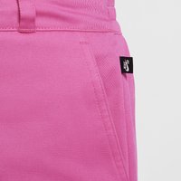 Rózsaszín farmernadrág, derékrésszel és oldalsó zsebekkel, a zseb szélén jól látható fekete Nike címkével.