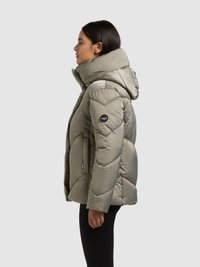 Mīkstināta zaļā krāsā pūdera jaka ar augstu apkakli un kapuci, rakstaina kviltēta struktūra un logo uzšuve kreisajā plecā.