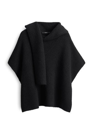 Poncho nero lavorato a maglia con un ampio colletto e una sciarpa abbinata appoggiata sulla spalla su uno sfondo bianco.