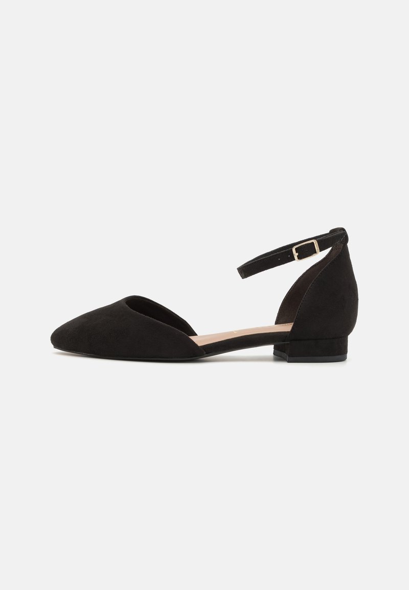 Chaussure femme en daim noir à talon bas, bout pointu, bride à la cheville et petite boucle dorée, présentée de profil sur fond blanc.
