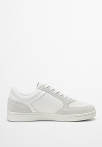 Sneaker grigio chiaro con tomaia in pelle e suede, lacci bianchi, punta perforata e suola in gomma con elementi di design minimalisti.