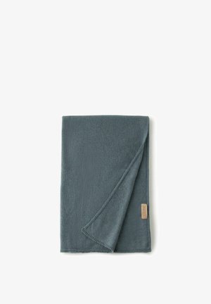 Mjuk, mörk teal-färgad filt med en slät textur, med en vikning i hörnet och en liten beige etikett på ena sidan. Kanterna är prydligt sydda.