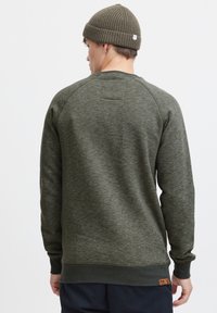 Groene sweatshirt met een gestructureerde afwerking, geribbelde manchetten en een logopatch aan de zoom. Voorzien van een ronde hals en raglanmouwen.