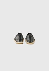 Svart og hvit vevd espadrillo-sko med en teksturert stoffoverdel og svarte skinnakenter. Naturlig jute-mellomsåle med sømdetaljer.