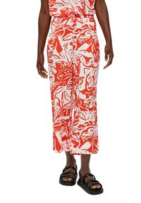 Czerwono-białe spodnie w kwiatowy wzór z elastycznym pasem, szerokimi nogawkami i gładką fakturą, w połączeniu z czarnymi sandałami.