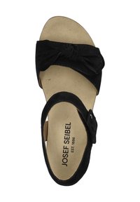 Sort ruskindsandal med en knyttet design foran, justerbar rem og en polstret sål med branding på indersålen.