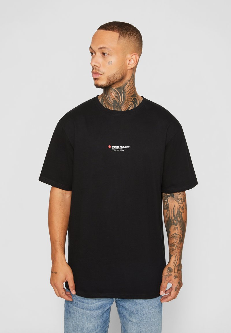 T-shirt de algodão preto com gola redonda, mangas curtas e um pequeno logotipo vermelho e branco no peito. Ajuste casual e textura suave.