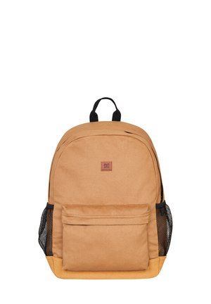 Mochila de tela marrón con forma redondeada, bolsillo frontal, dos bolsillos laterales de malla y un asa superior resistente. Presenta un parche con el logo.