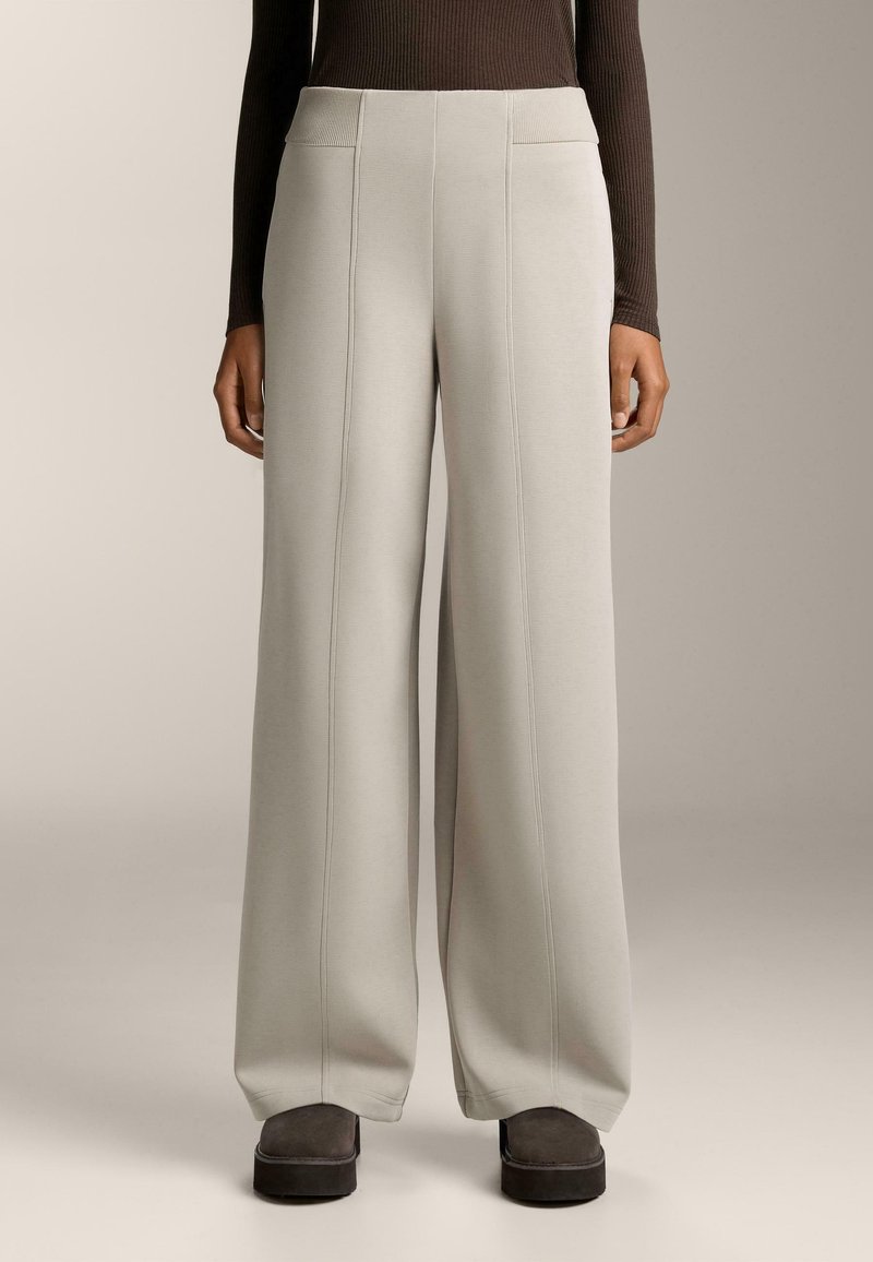 Široke hlače iz svetlo sive tkanine z vidnimi šivi. Imajo visok pas in stranske žepe. Nosi se z temno obutvijo.