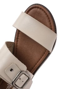 Sandal in pelle beige con due ampi cinturini, plantare imbottito marrone, dettagli in fibbia argentata e suola testurizzata.