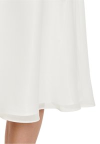 White, flowing dress made of lightweight, sheer fabric. Features a smooth texture and a hemmed bottom. Ends just above the knee.
